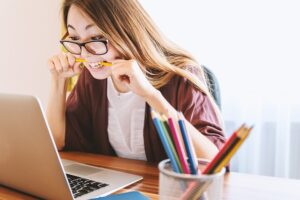 woman at a laptop biting a pencil